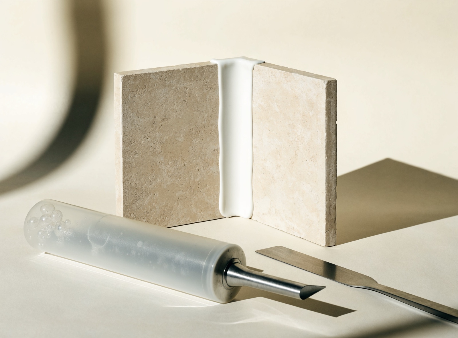 Materialaufnahme: Silikonkartusche, Fugenglätter und Abklebeband auf einer hellen Fliesenfläche